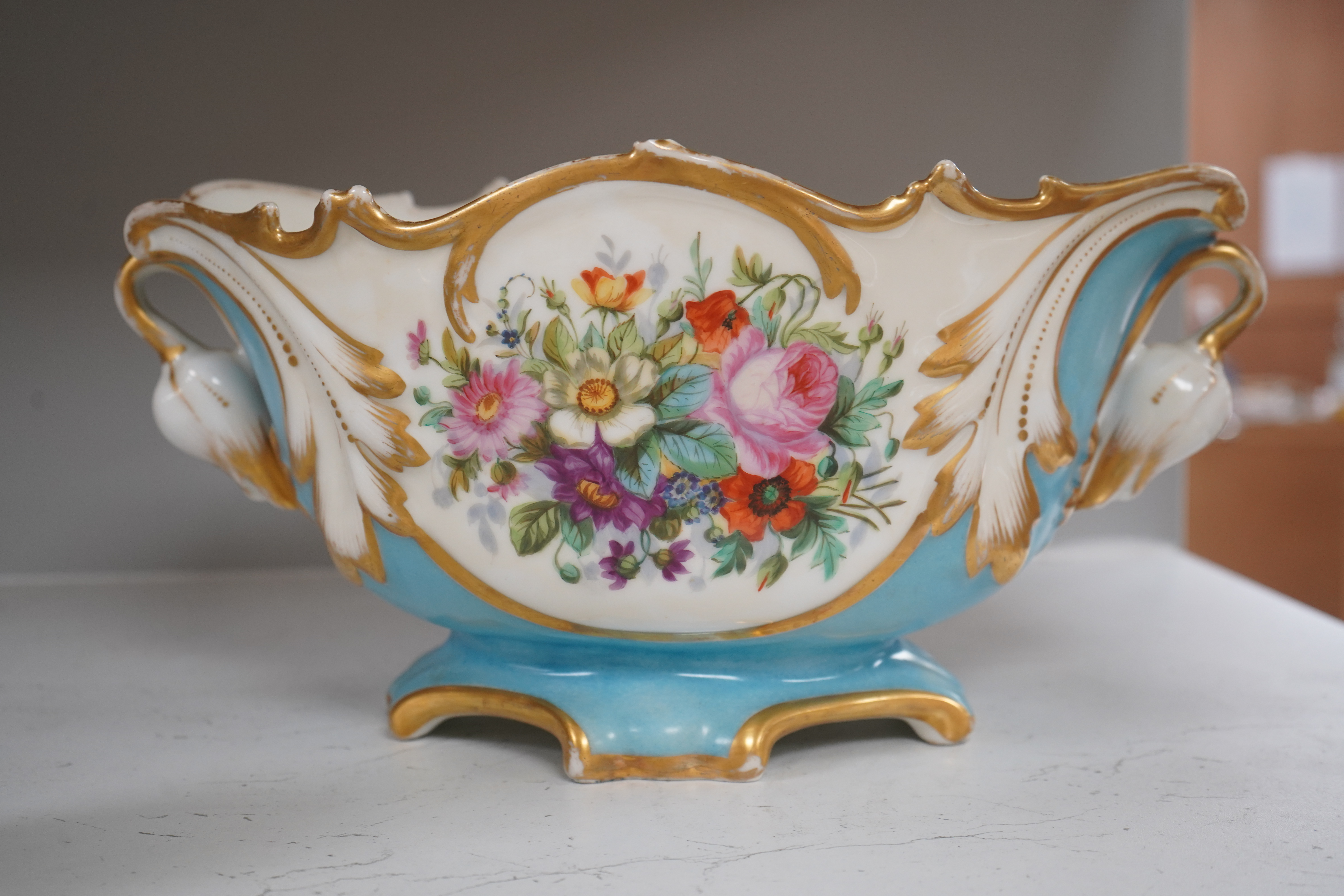 A Sevres style flower painted navette shaped jardiniere and a similar French scent bottle and stopper, late 19th century, largest 38cm wide. Condition - fair to good